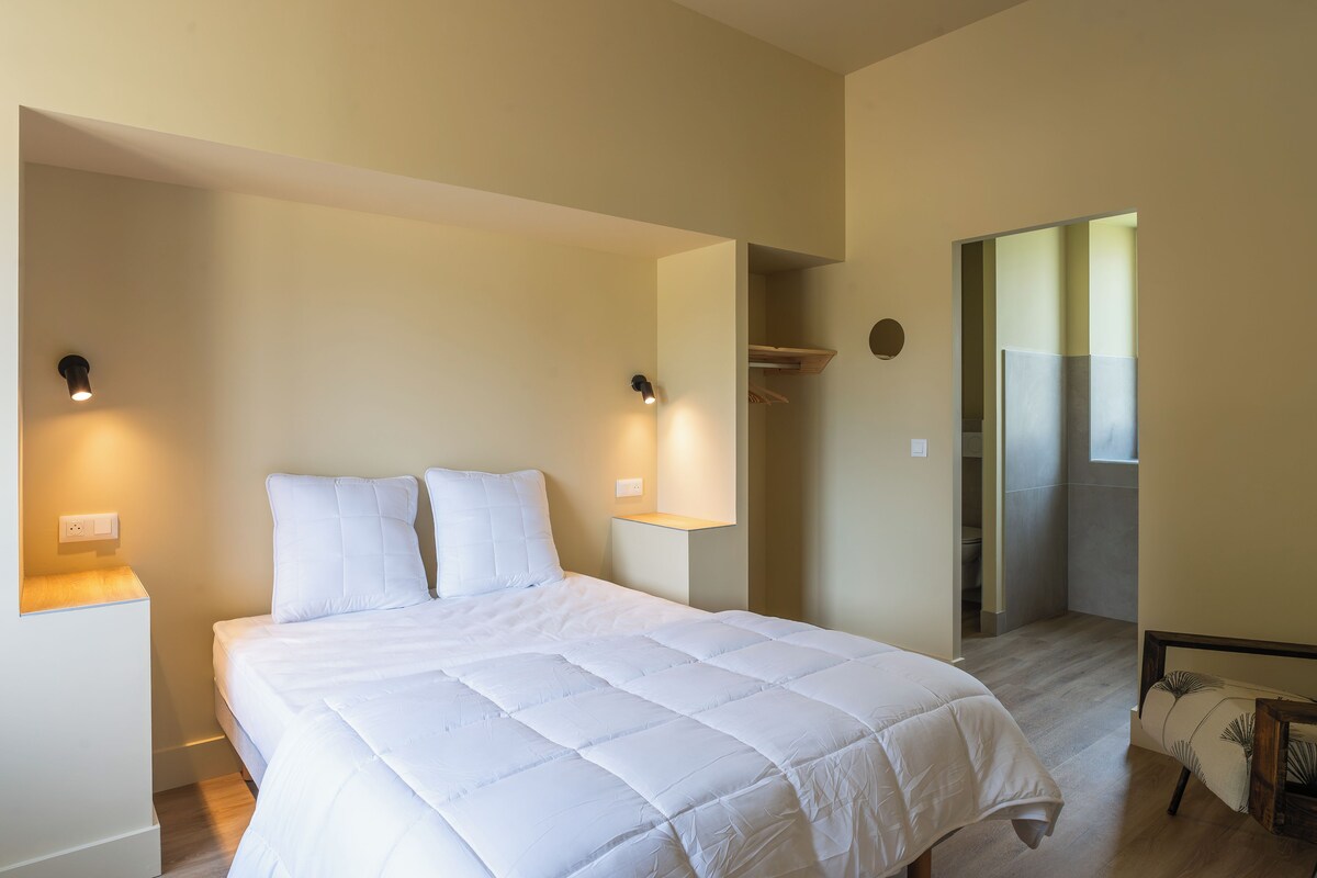 Un dormitorio con una cama grande, dos lámparas de noche y vistas al baño.