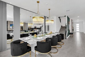 A modern dining area with a long table set for a meal, elegant chandeliers, and a staircase leading to another level. - Stunning 9BR Themed Villa | Immersive Experience (Davenport)