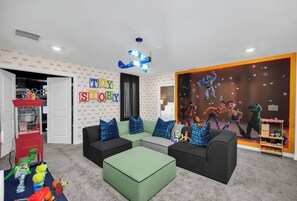 A children's playroom with a large toy story mural, a popcorn machine, and a cozy seating area. - Stunning 9BR Themed Villa | Immersive Experience (Davenport)
