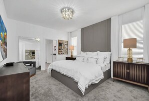 Une chambre d’hôtel moderne avec un grand lit, des lampes de chevet, une commode et un miroir.