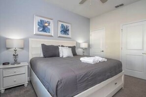 Ein Schlafzimmer mit einem Bett, zwei Nachttischlampen, einem Nachttisch und zwei Wandbildern.
