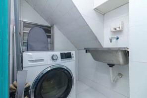 A compact laundry room with a washing machine, a drying rack, and a sink. - Studio in Ipanema • Next to the Beach and Lagoon (Rio de Janeiro)