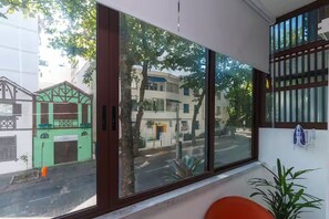 A room with a large window, a plant, and a chair. - Studio in Ipanema • Next to the Beach and Lagoon (Rio de Janeiro)