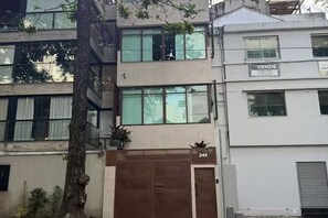 Un edifici de diverses plantes amb una porta tancada, un número d'adreça visible i un senyal que indica un negoci anomenat 'Vende'.