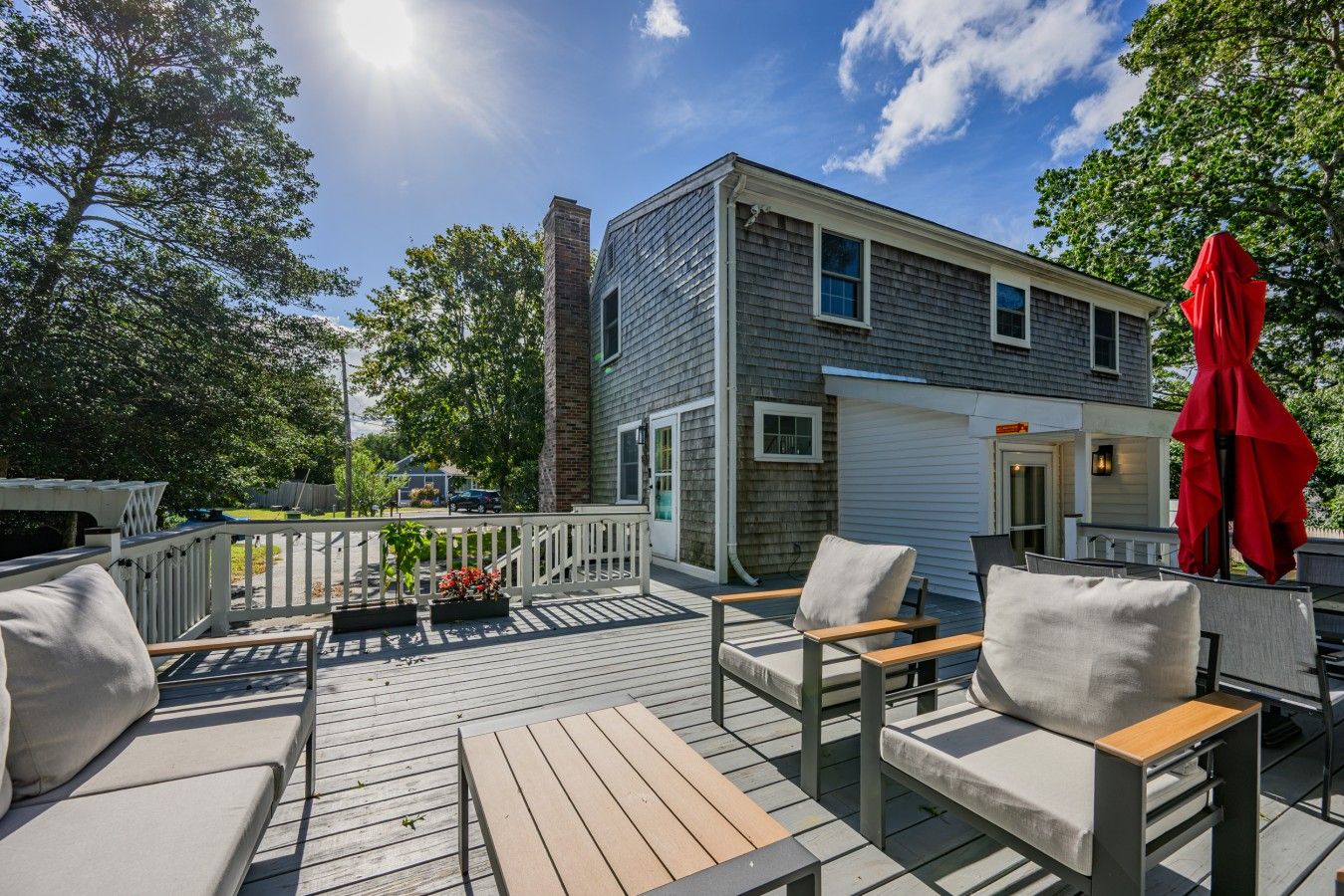 A deck with outdoor furniture and a red umbrella.