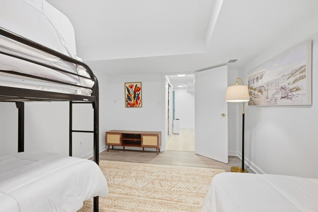A bedroom with bunk beds, a wooden cabinet, a patterned rug, and a painting on the wall.