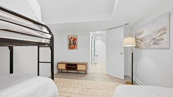 A bedroom with bunk beds, a wooden cabinet, a patterned rug, and a painting on the wall.