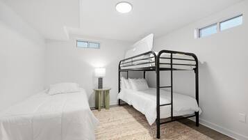 A room with bunk beds, a bedside table with a lamp, and a patterned rug.