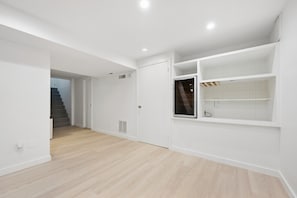 Een ruime kamer met een houten vloer, witte muren en een inbouwkast.