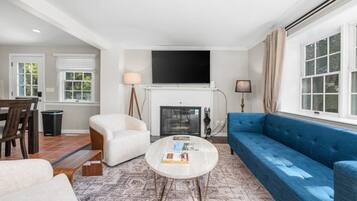 A living room with a fireplace, a sofa, a coffee table, and a television mounted above the fireplace.