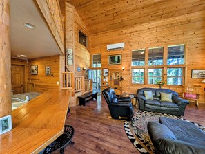 Een houten chalet van binnen, met een bar, zithoek en grote ramen.