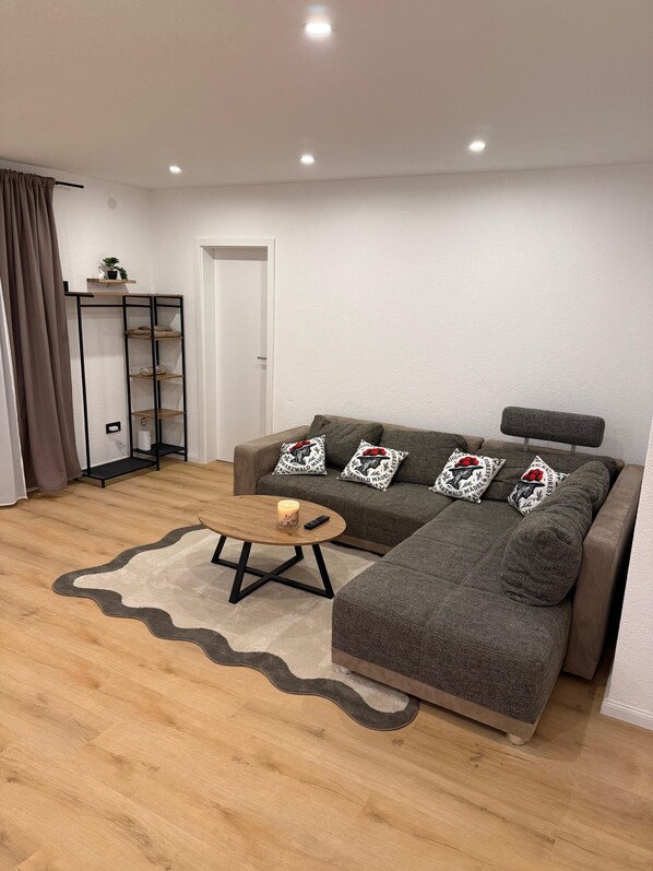 A modern living room with a sofa, a coffee table, and a bookshelf.