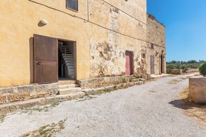 A building with a gravel driveway, a wooden door, and a staircase leading to an upper level. - Torretta Morelli by BarbarHouse (Sannicola)
