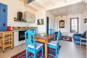 A modern kitchen with a dining area, a sofa, and a window. - Torretta Morelli by BarbarHouse (Sannicola)