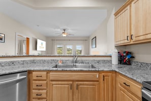 A kitchen with granite countertops, wooden cabinets, a stainless steel sink, and a ceiling fan. - Lakeside Leisure - Lake Views (Branson)