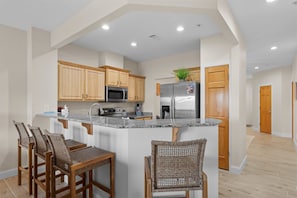 A modern kitchen with wooden cabinets, a stainless steel refrigerator, and a granite countertop. - Lakeside Leisure - Lake Views (Branson)