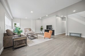 A spacious living room with a sofa, armchair, coffee table, and a TV on a stand. - Dreamy Duplex B-Spacious & Comfortable! 3 Bedrooms! (Hartford)