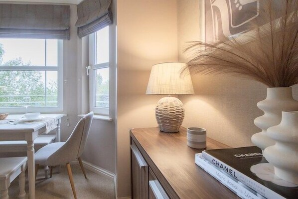 Ein Zimmer mit einem Holztisch, einer Lampe, einer Vase und einem Buch mit dem Titel 'SCHANEL'.