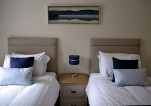 Ein Hotelzimmer mit zwei Betten, einem Nachttisch mit Lampe und einem Bild an der Wand.