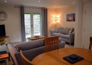 A living room with a sofa, a table, and a TV. - 6 Cara Anan- 2 Bedroom House (Stirling)