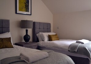 Een hotelkamer met twee bedden, een nachtkastje, een lamp en een ingelijst beeld aan de muur.