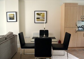 A compact living space with a sofa, a dining table with chairs, and a kitchenette. - 12 Alainn Eve - 2 Bedroom House, Killin (Stirling)