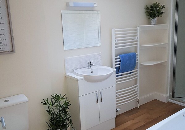 A bathroom with a white sink, mirror, and towel rack. - 12 Alainn Eve - 2 Bedroom House, Killin (Stirling)