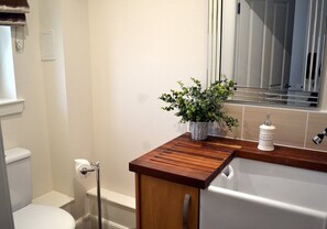 Ein Badezimmer mit einem Holzkonsolenunterschrank, Toilette, Waschbecken und Spiegel.
