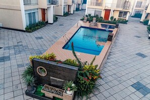 A rooftop pool area with a rectangular pool, surrounded by potted plants and a wooden deck. - 5 minutes to the theme park! Family-sized condo with game room & deck (Dar es Salaam)