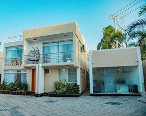 A modern two-story building with a balcony, large windows, and a glass door entrance. - 5 minutes to the theme park! Family-sized condo with game room & deck (Dar es Salaam)