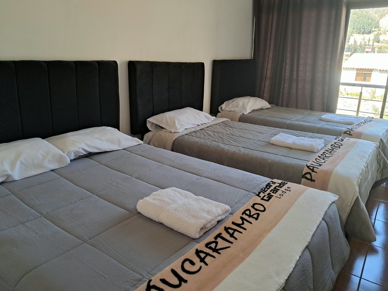 Habitación de hotel con tres camas, cada una con cabecero y almohadas.