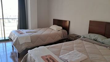 A hotel room with two beds, a nightstand, and a view through a window.