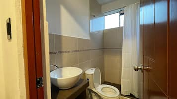 A bathroom with a toilet, sink, and shower.