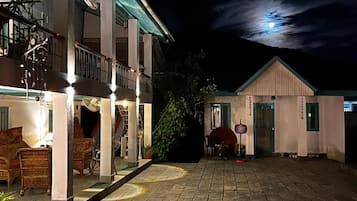 A hotel courtyard with a stone floor, outdoor seating, and a building with a balcony.