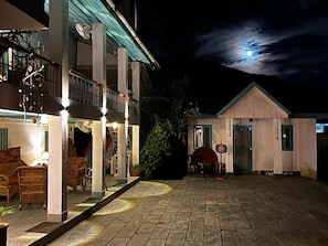 Un patio de hotel con piso de piedra, mobiliario exterior y un edificio con balcón.