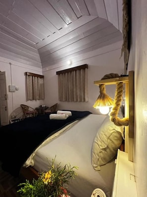 A room with a bed, a bedside lamp, a chair, and a small table. - Moonshine Villa (Bir)