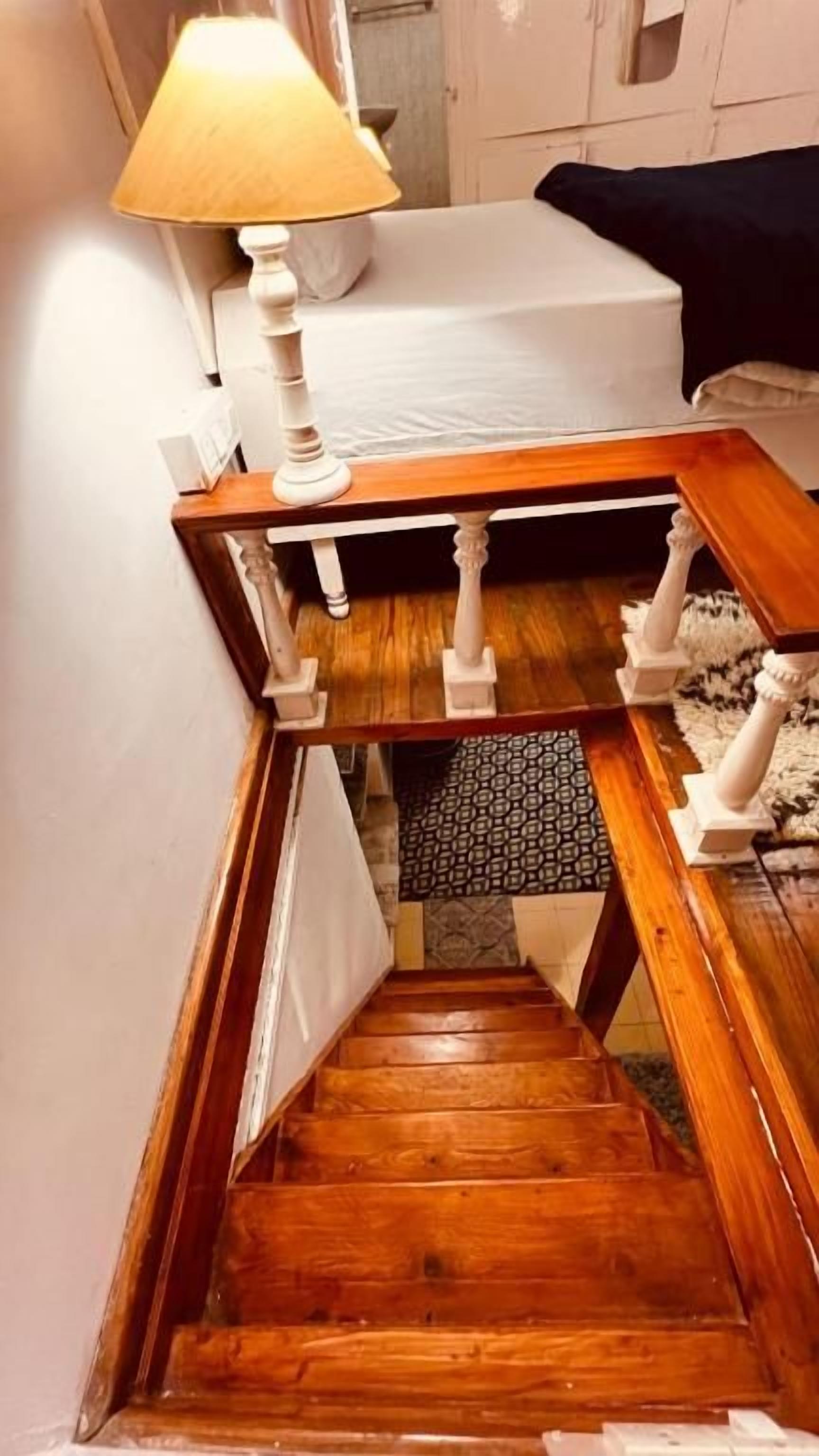 A wooden staircase with a lamp on the landing.