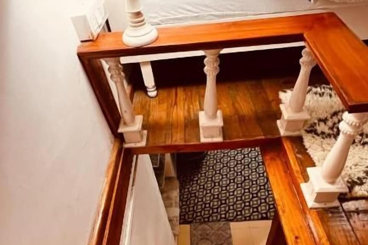 Una escalera de madera con una lámpara en el rellano.