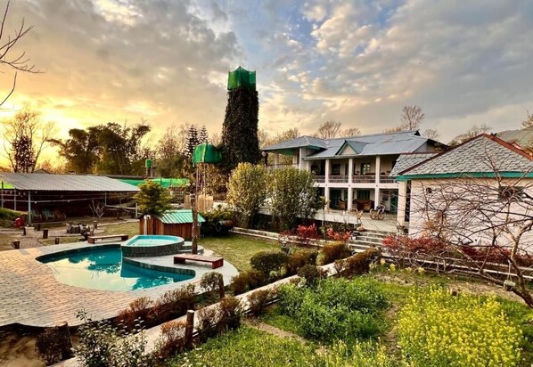 Una zona residencial con piscina, una estructura alta de color verde y una casa con balcón.