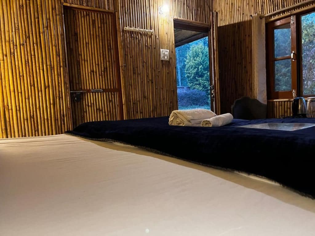 A room with a bed, a wooden door, and a view of the outdoors.