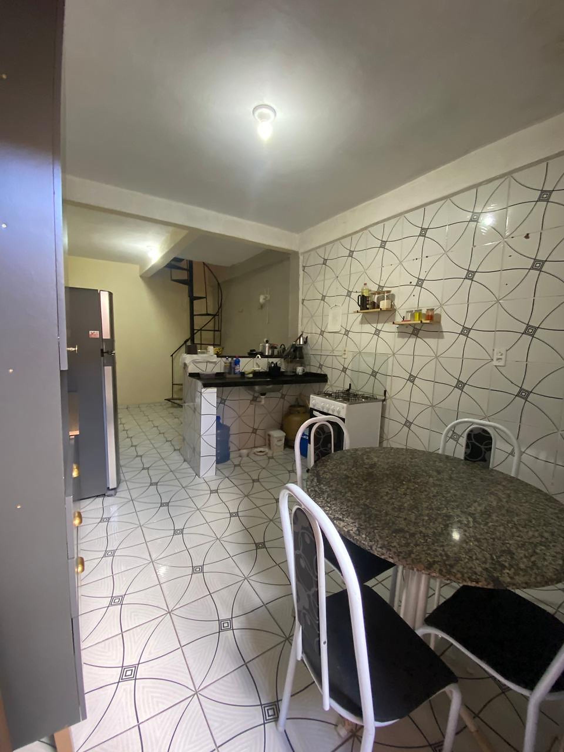 Cozinha com área de jantar, apresentando backsplash de azulejos, fogão e geladeira.