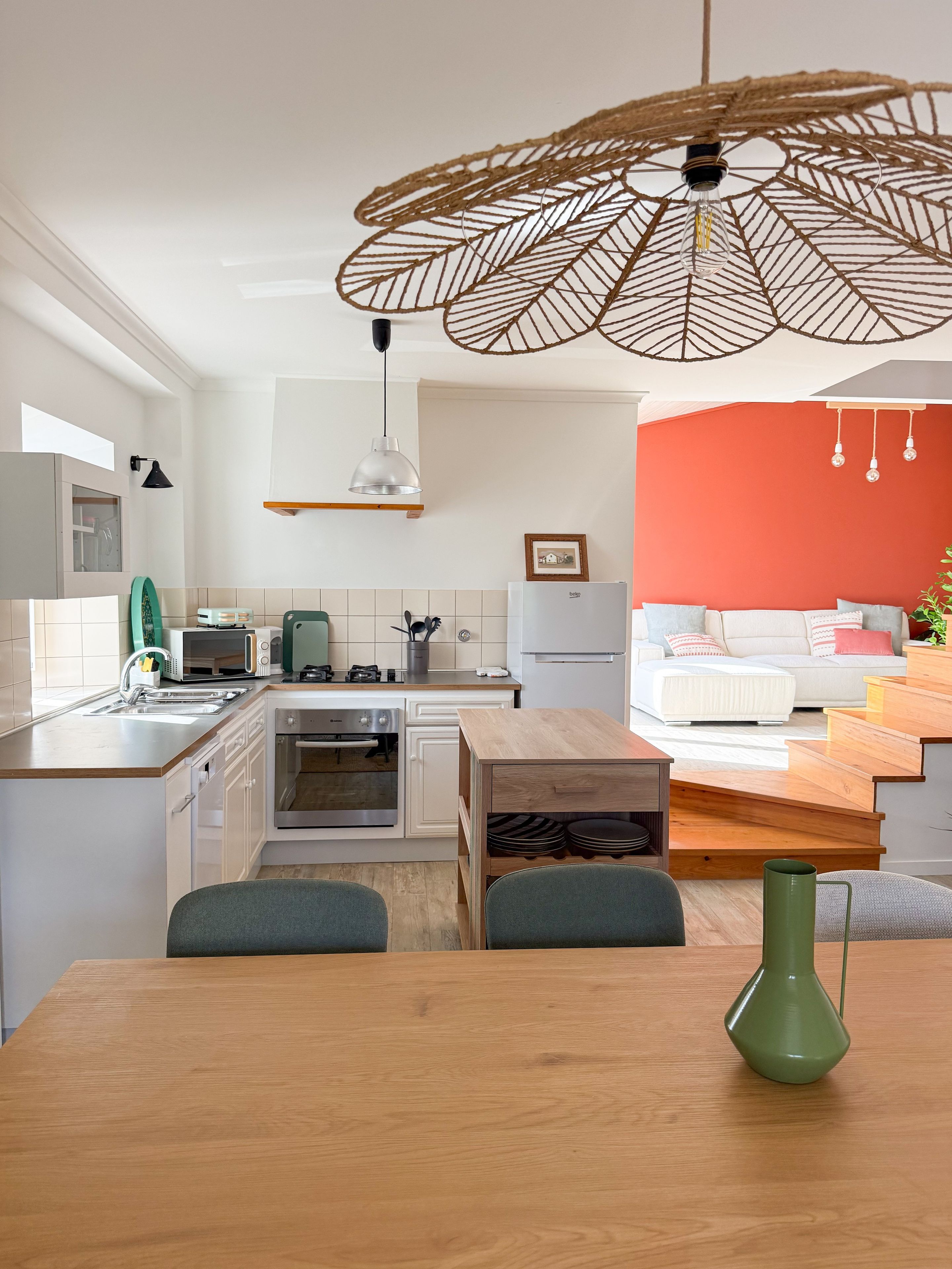 Een moderne keuken met witte kasten, een houten eettafel en een groene vaas.