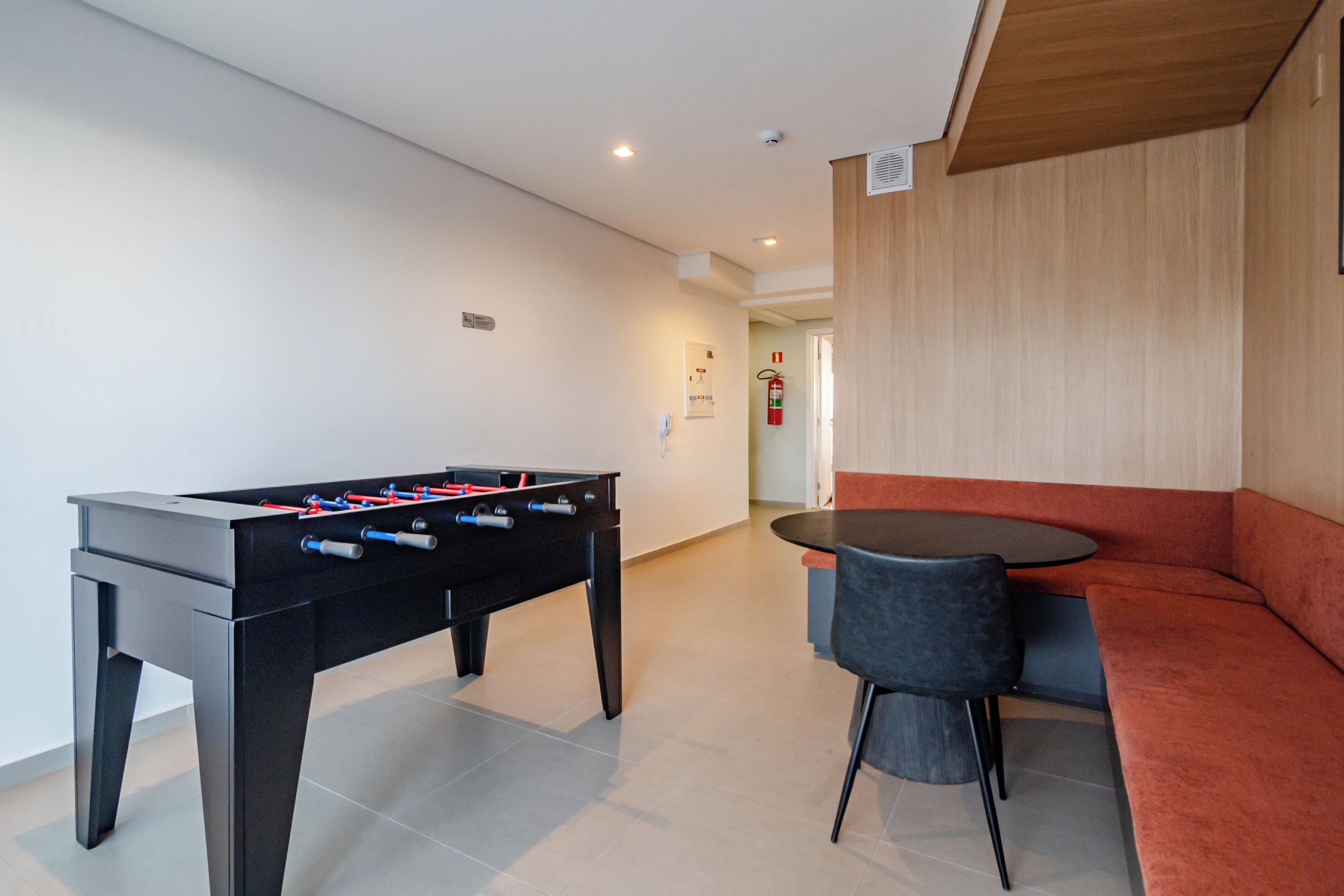 Una habitación con una mesa de fútbol, un sofá y una pequeña mesa con sillas.