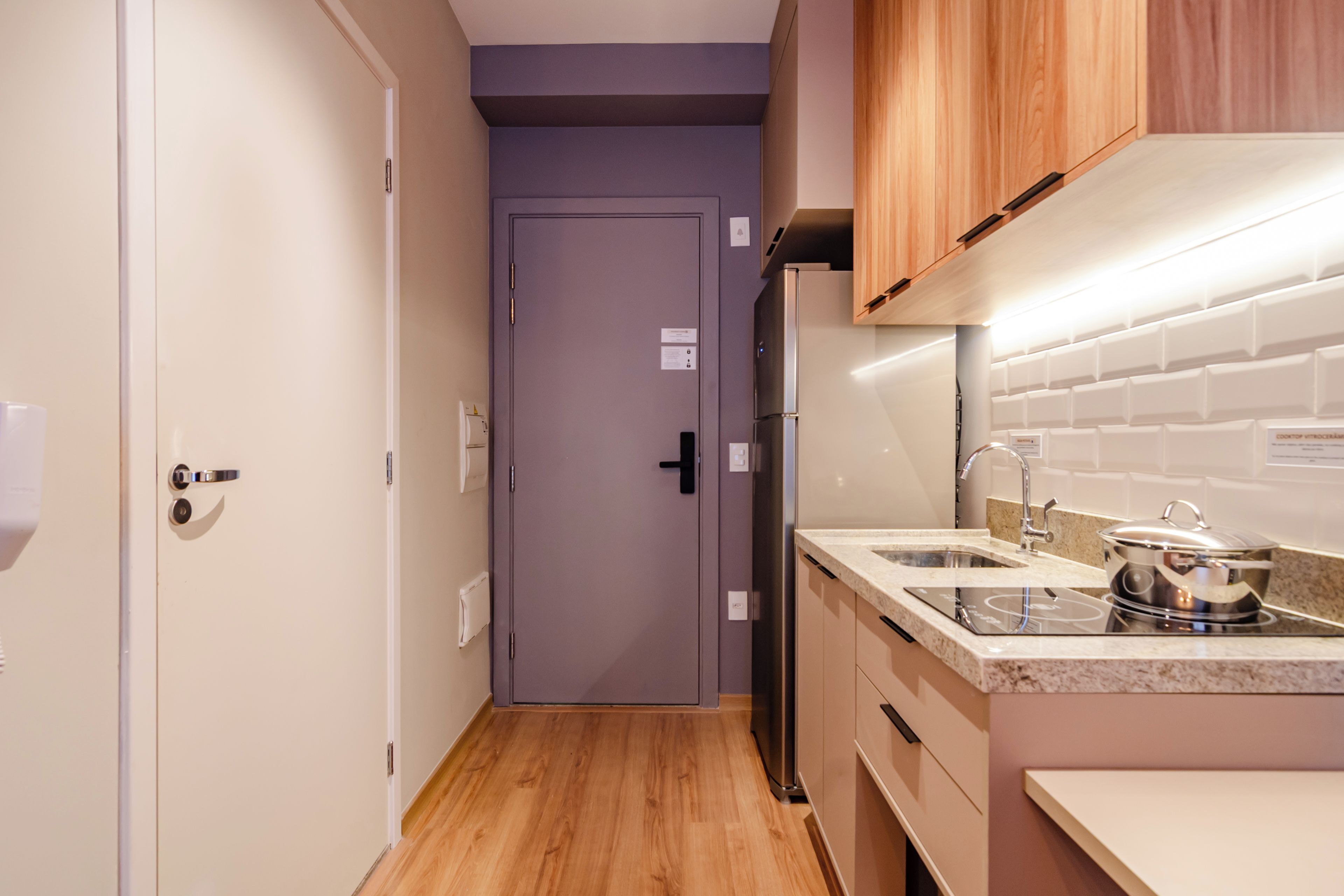 Una cocina estrecha con armarios de madera, un refrigerador de acero inoxidable y una encimera con fregadero y estufa.