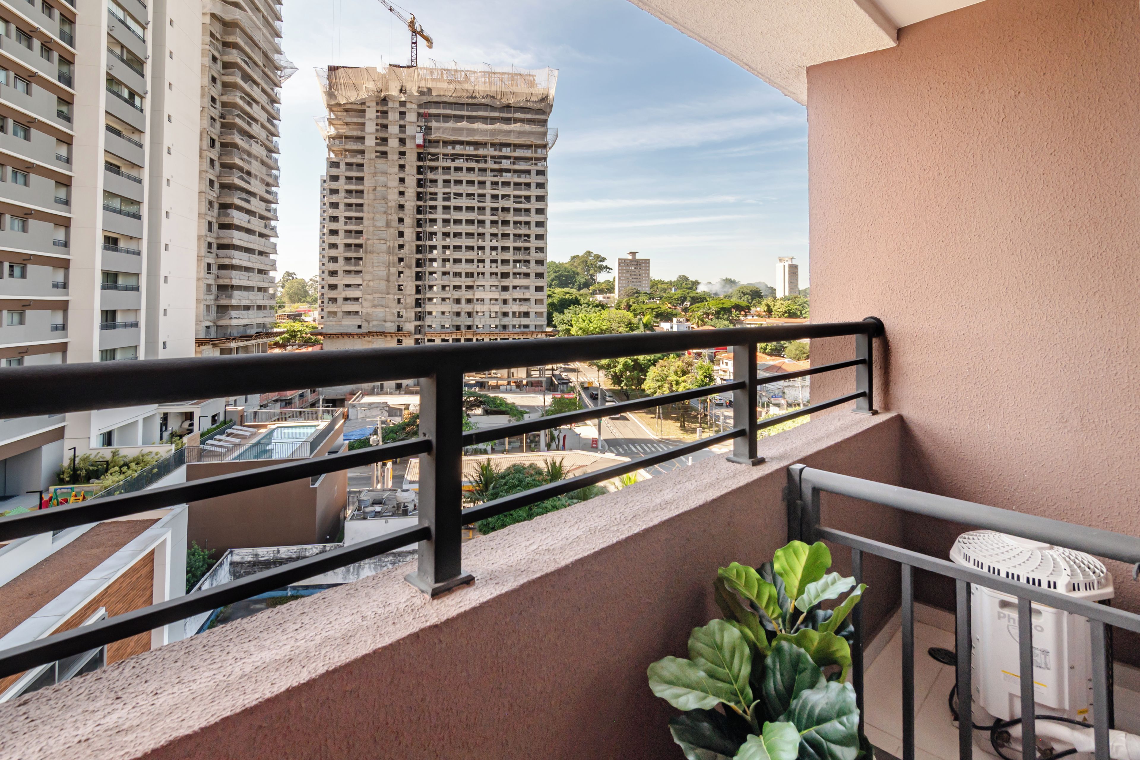 Un balcón con vistas a un paisaje urbano, que incluye edificios altos y una obra en construcción.