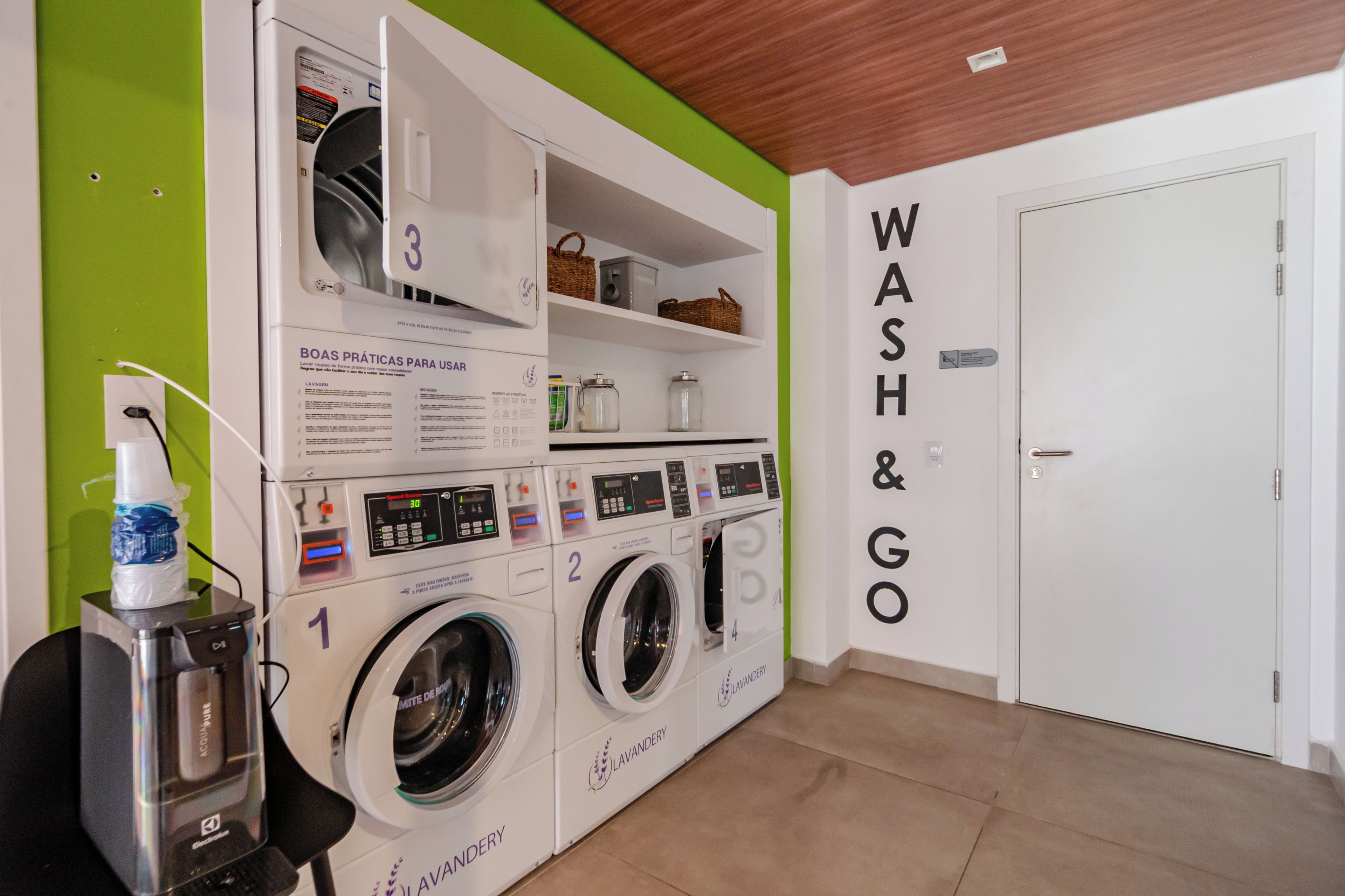Un cuarto de lavandería con varias lavadoras, una secadora y un dispensador de agua.