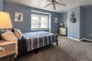 A bedroom with a bed, a nightstand, a dresser, a ceiling fan, and a window. - Summit Row | Both Houses (Pittsburgh)