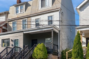 A multi-story residential building with a front porch, a staircase, and a small garden area. - Summit Row | Both Houses (Pittsburgh)