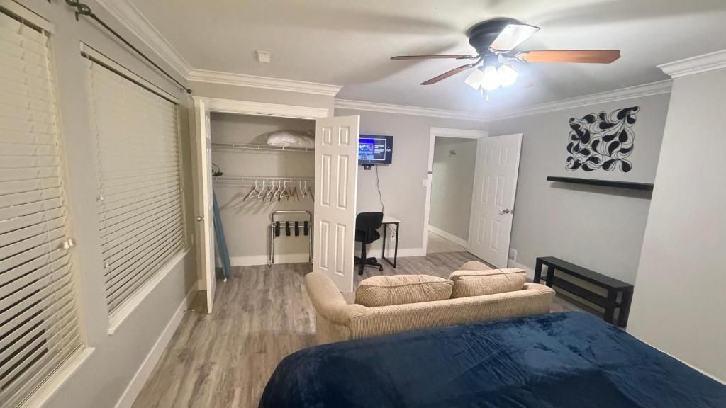 A bedroom with a bed, a ceiling fan, a TV, and a walk-in closet.