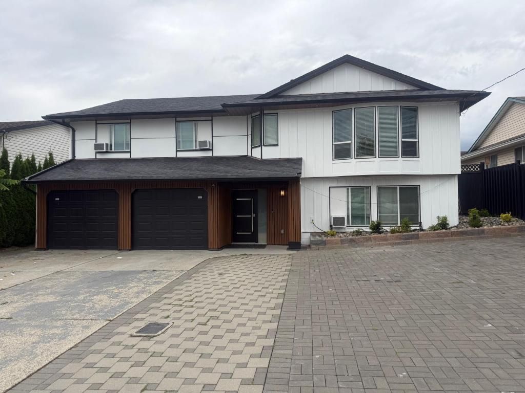 A two-story residential building with a garage, a paved driveway, and a landscaped front yard.